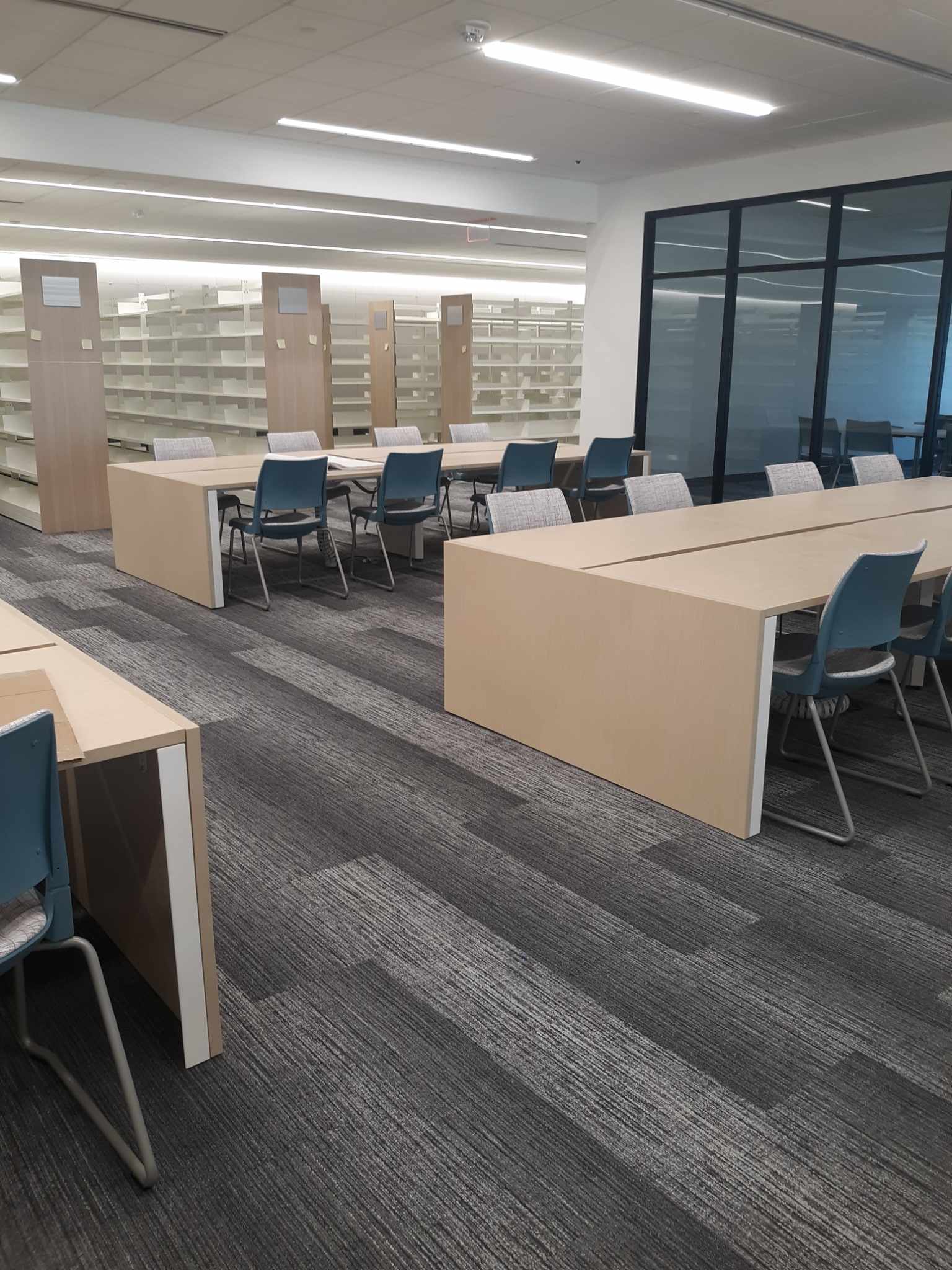 Empty bookshelves and tables in the new west side area of the building.
